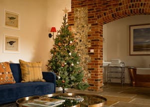 Artificial christmas tree next to blue sofa