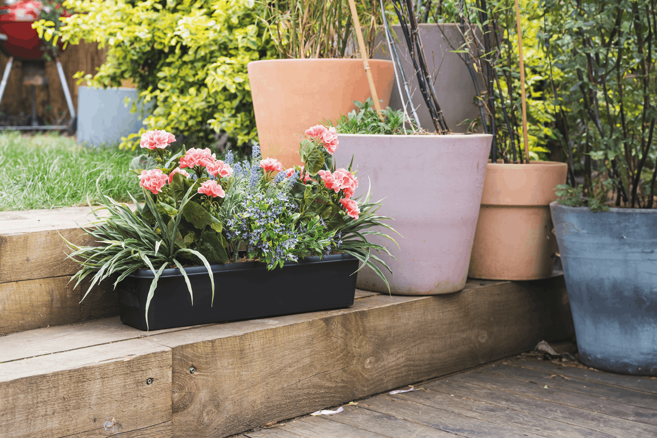 Artificial pink mixed flower window box on wooden garden steps