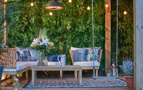 Artificial outdoor seating area with faux bouquet and artificial green wall