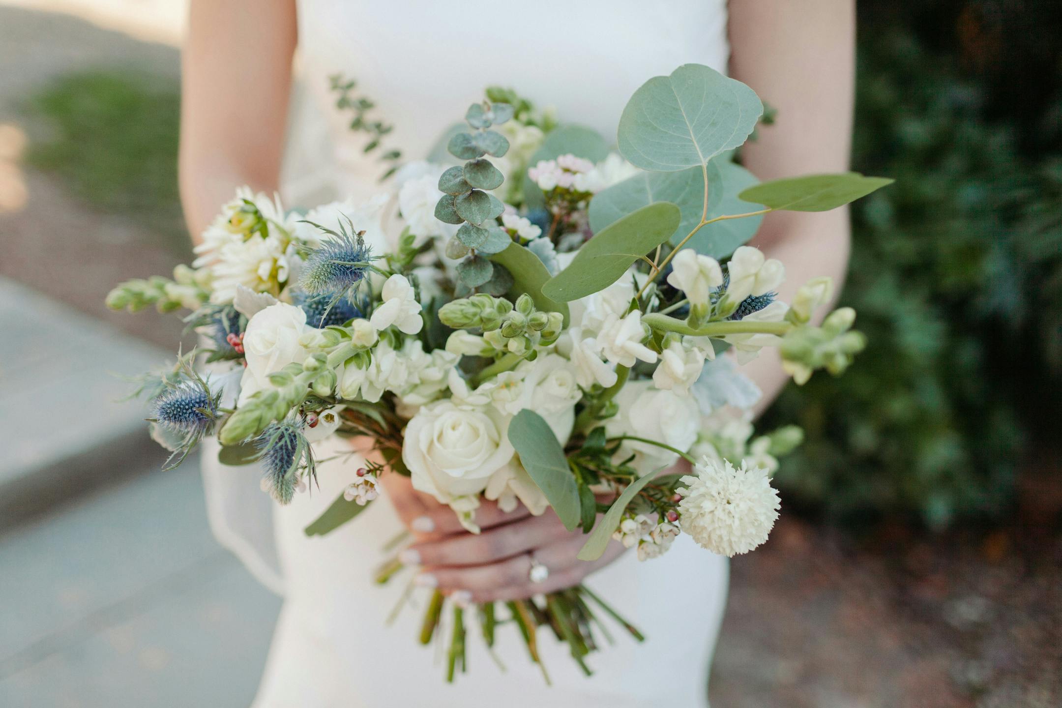 Woman in wedding dress holding white wedding bouquet with eucalyptus
