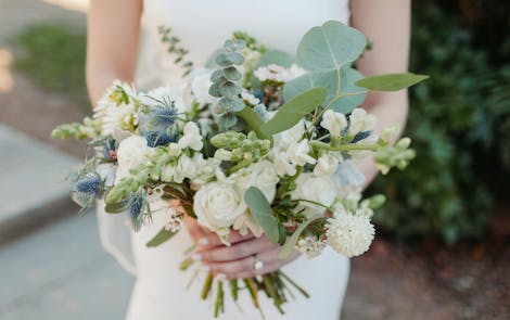 Woman in wedding dress holding white wedding bouquet with eucalyptus