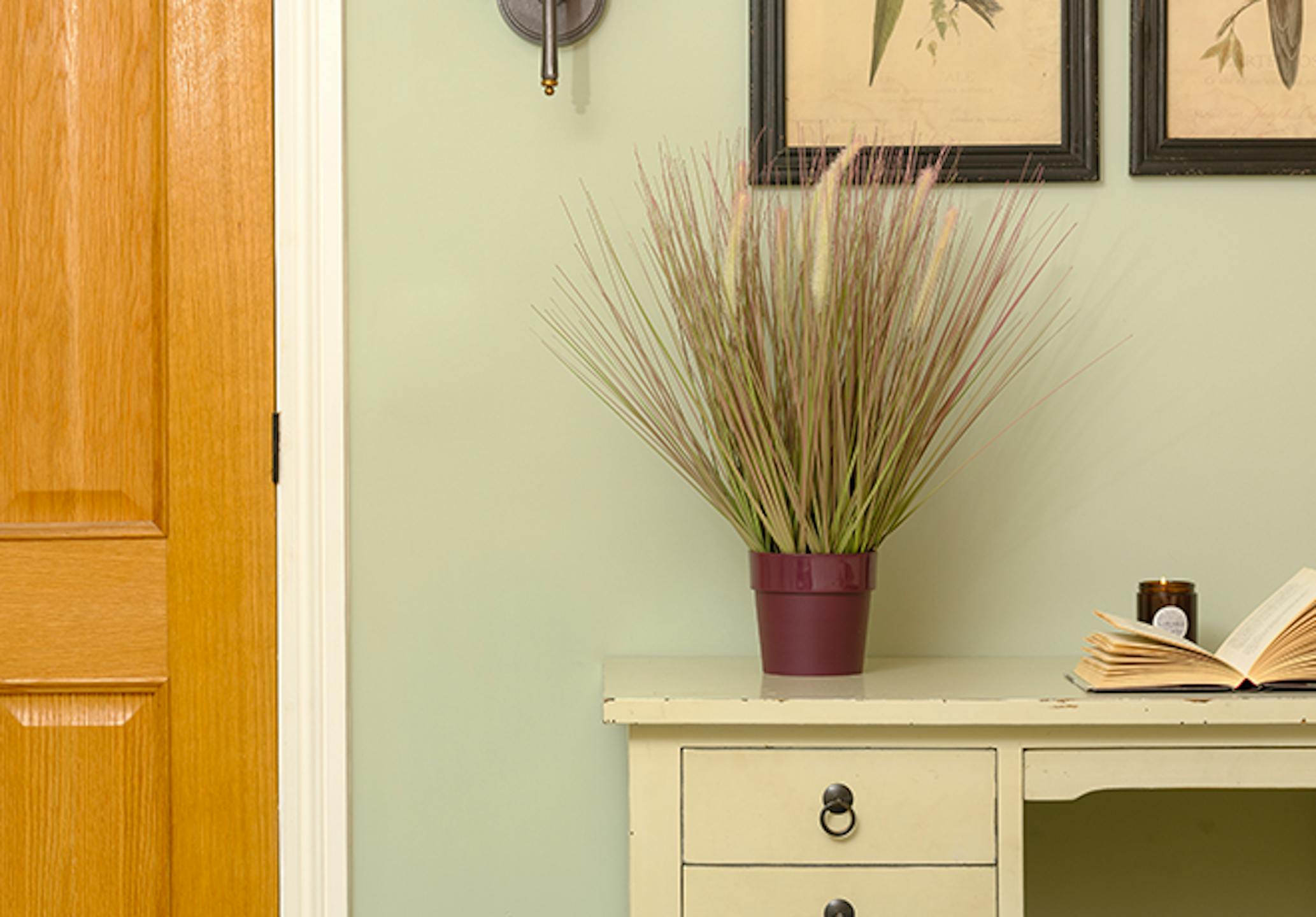 Faux pennisetum grass on white desk in blue room