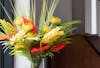 Tropical artificial flower bouquet of red and yellow flowers with palm foliage