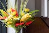 Tropical artificial flower bouquet of red and yellow flowers with palm foliage