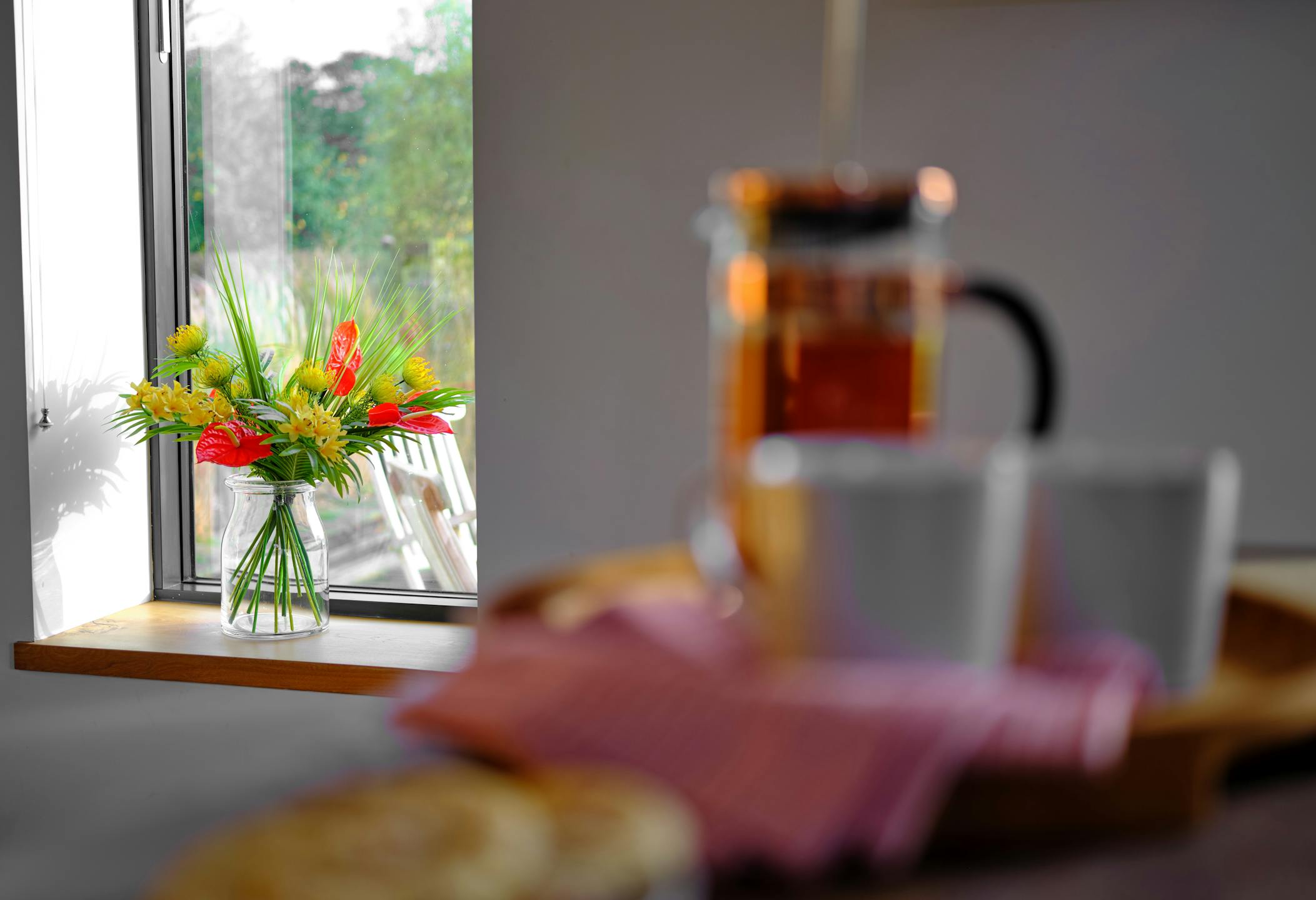 Artificial bahama mama bouquet on wood kitchen window ledge