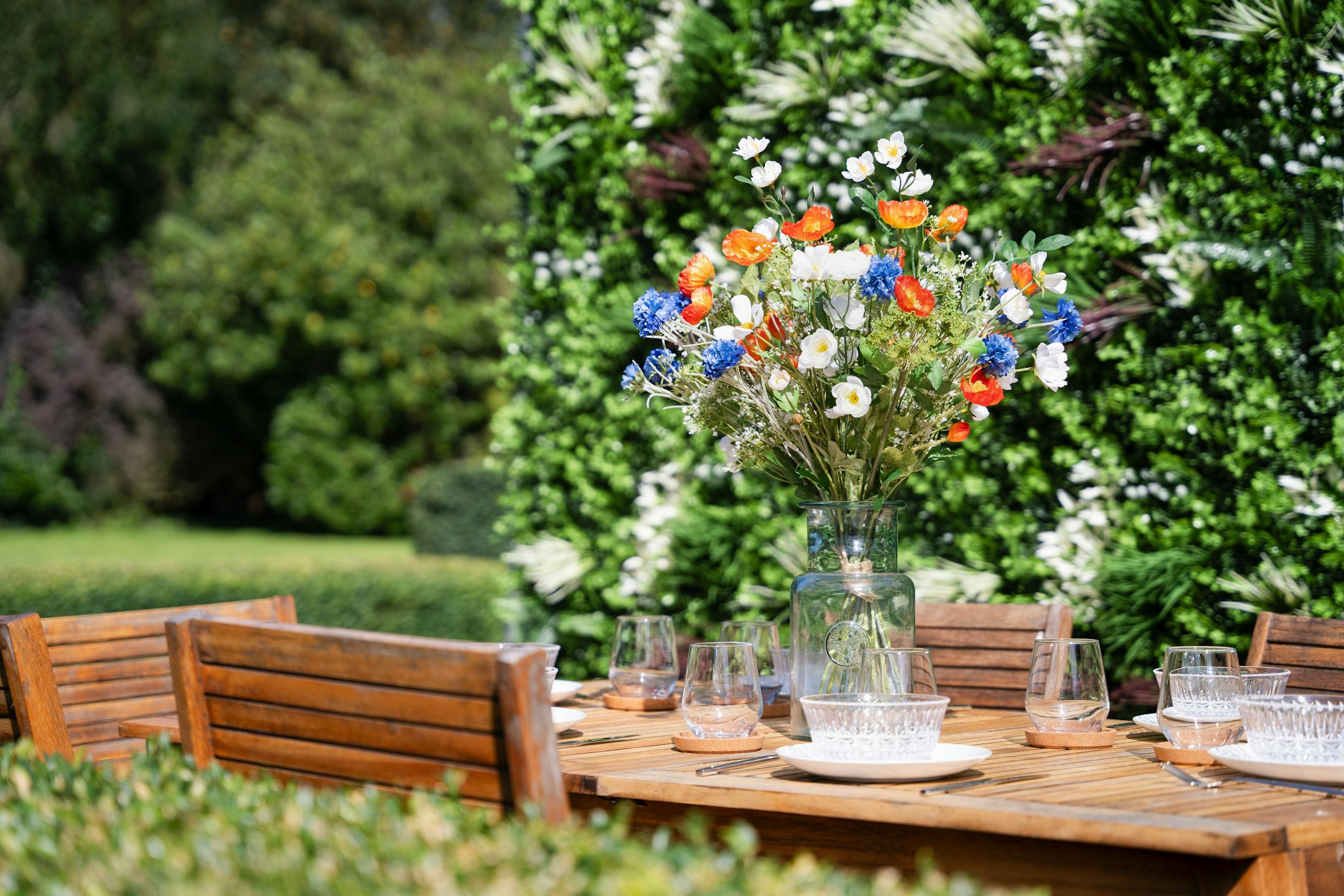 Artificial meadow bouquet on outdoor dining table with green living wall