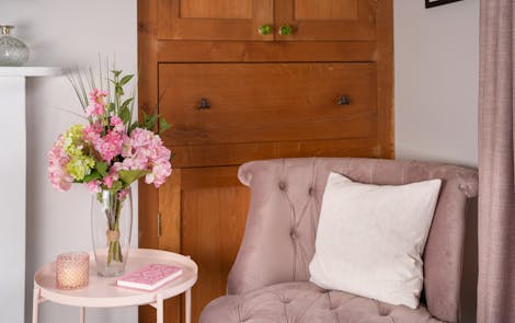 Artificial pink passion bunch on pink side table with pink velvet chair