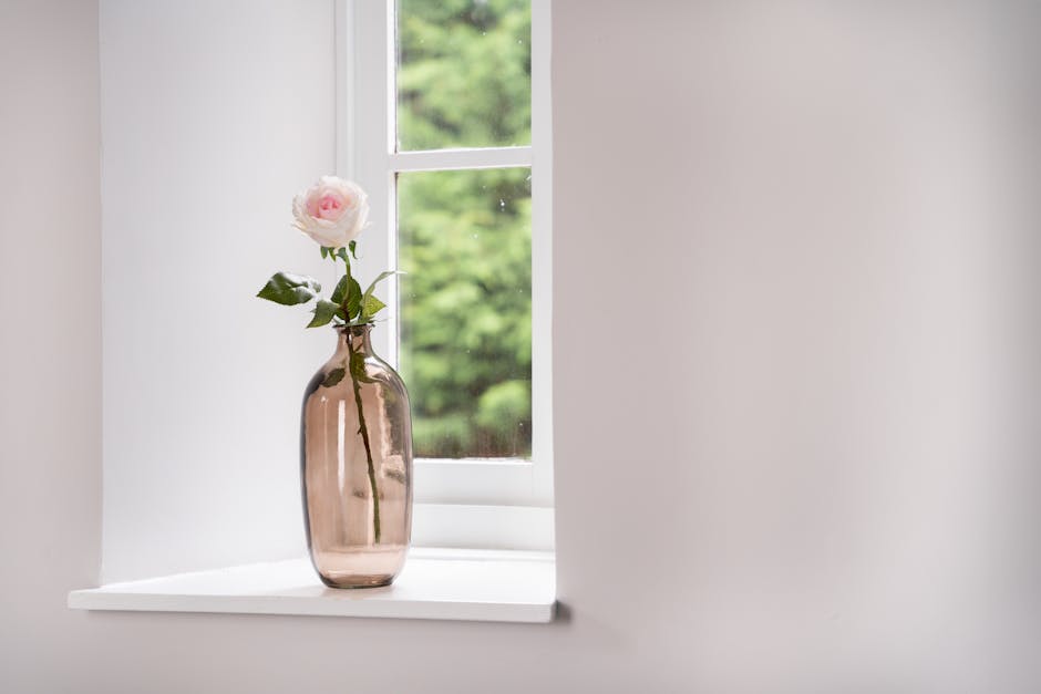 Artificial white pink rose stem in vase on windowsill