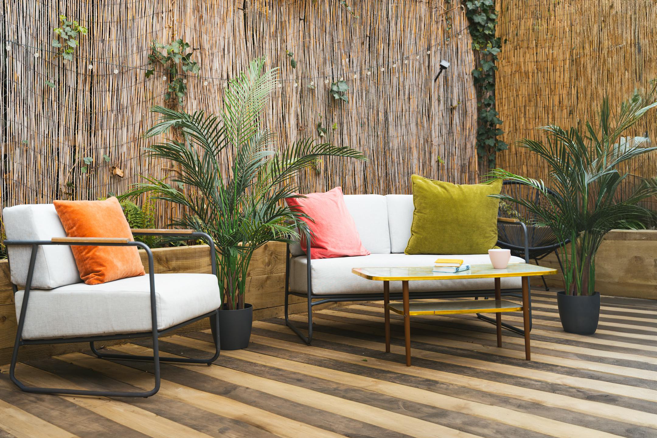 Artificial areca palm tree on garden decking with chairs and table