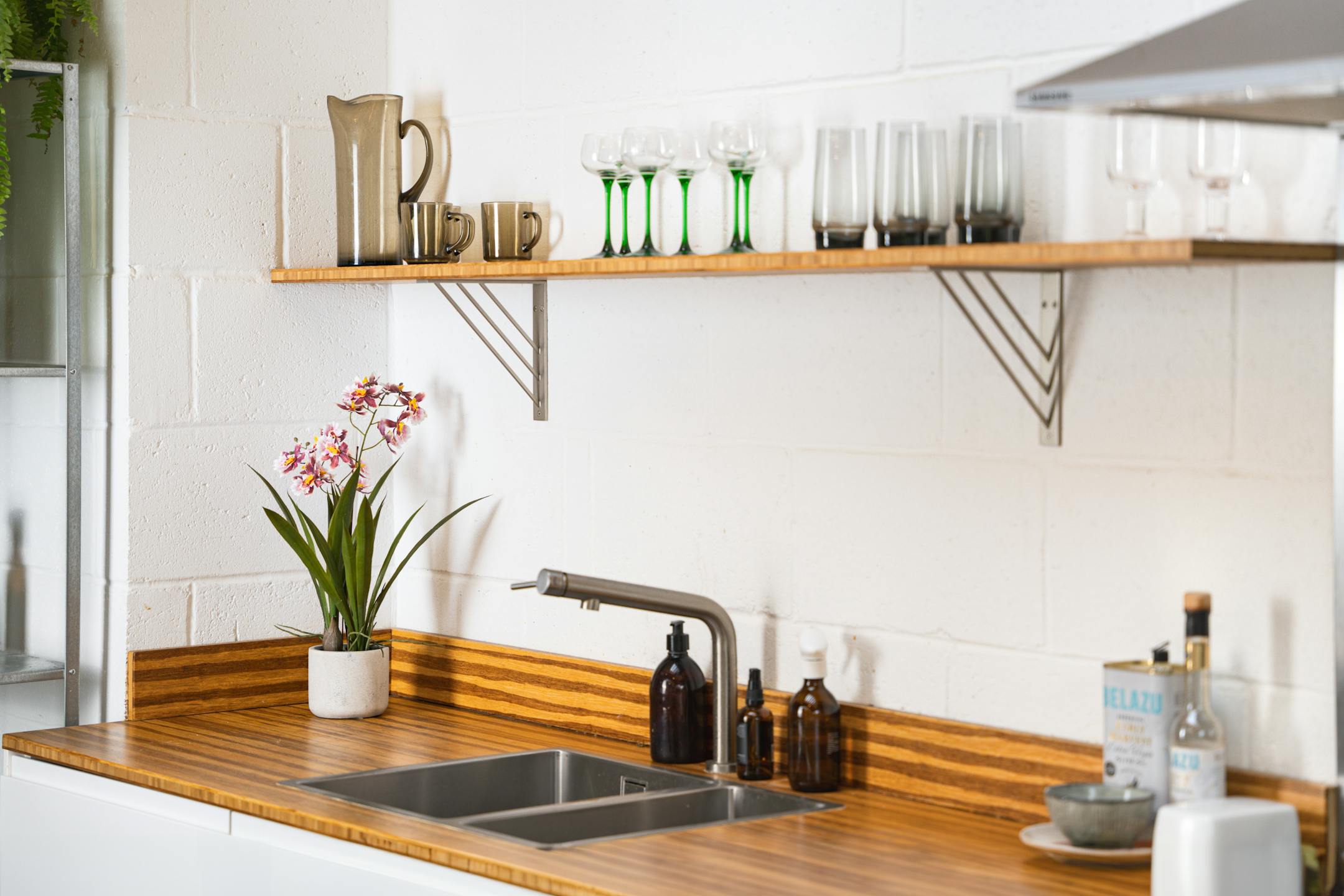 Artificial pink onicidium orchid on wooden worktop in white kitchen