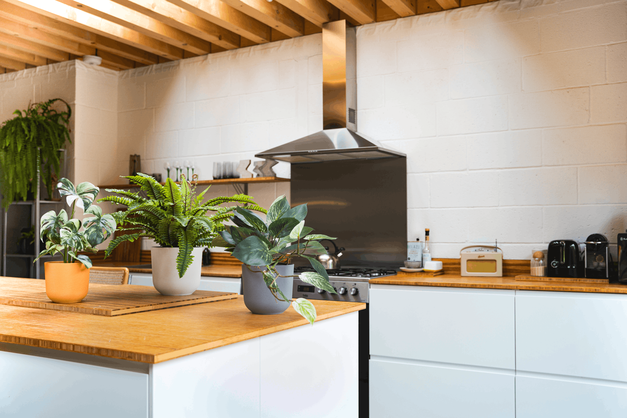 Small artificial plants in colourful pots on kitchen worktop