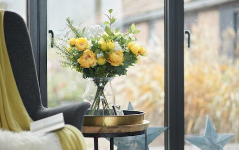 Yellow peony sensational bouquet on side table in front of large window