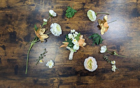 Artificial buttonhole on table surrounded by other foliage
