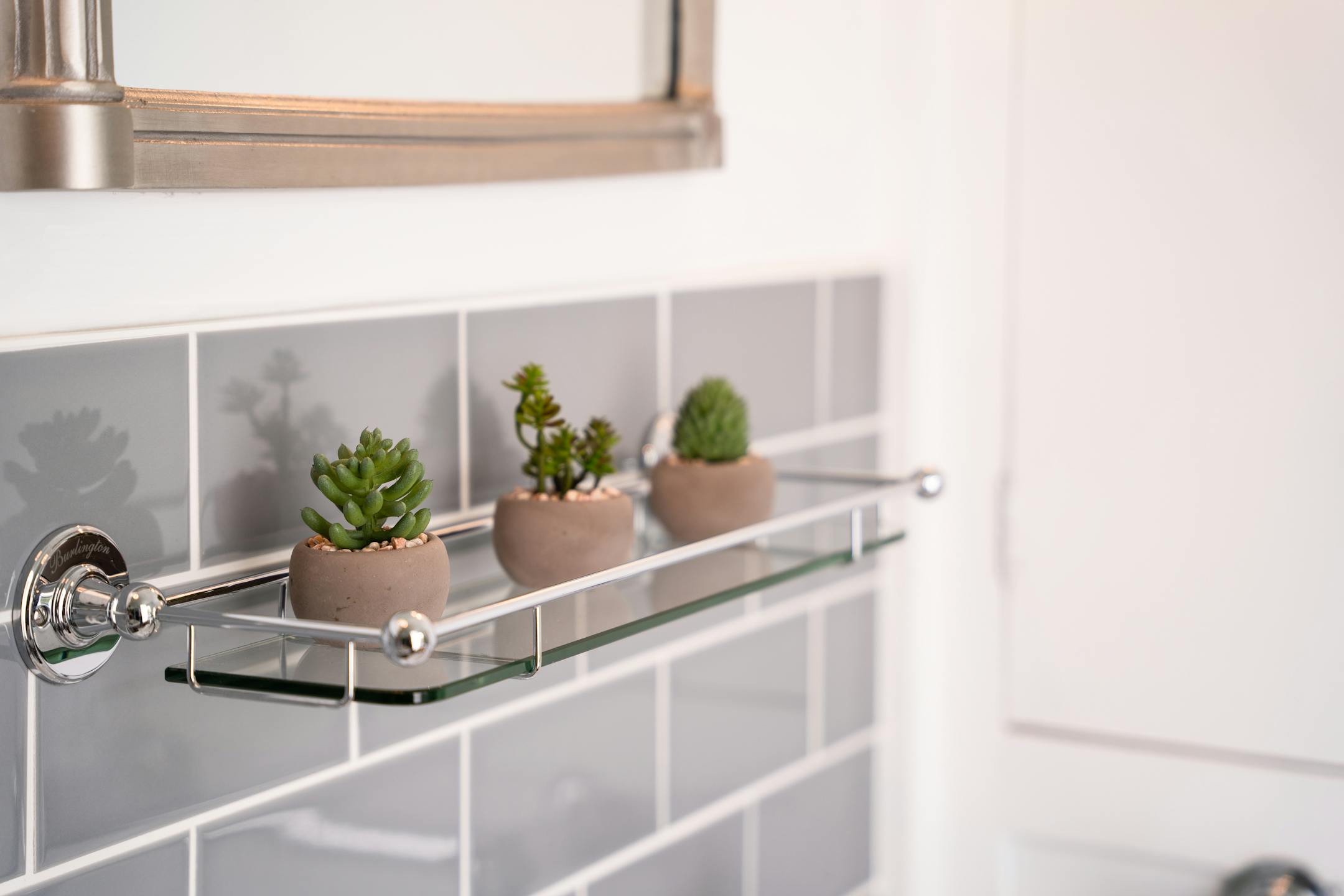 Mini artificial succulent trio on shelf in grey bathroom