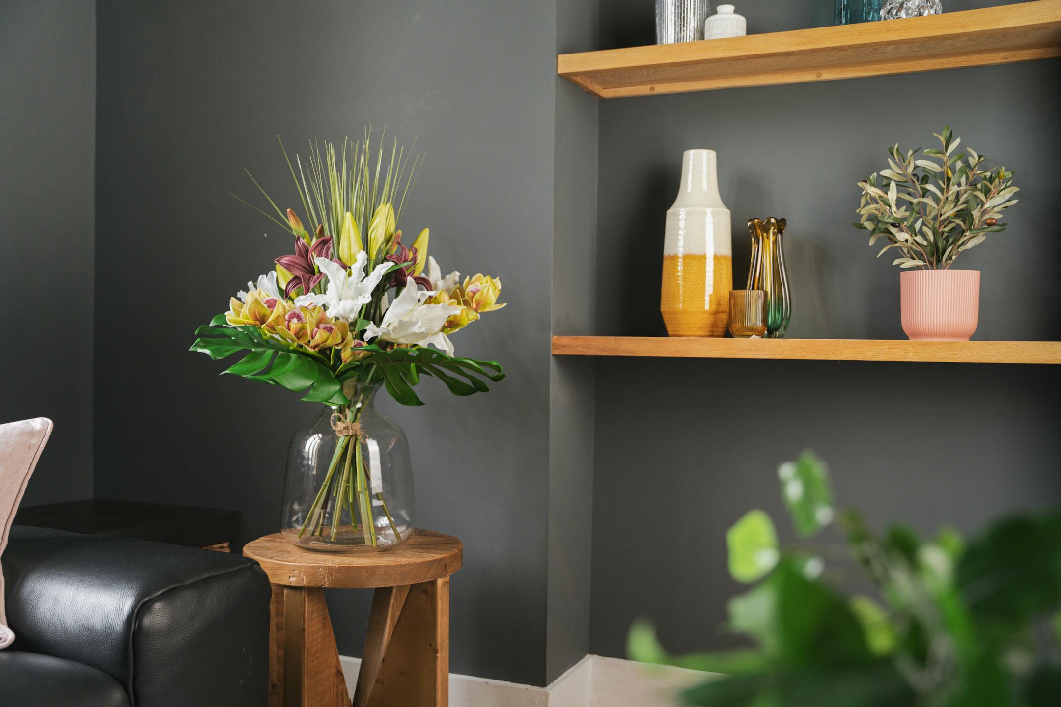 Artificial exotic bouquet against navy wall with shelves