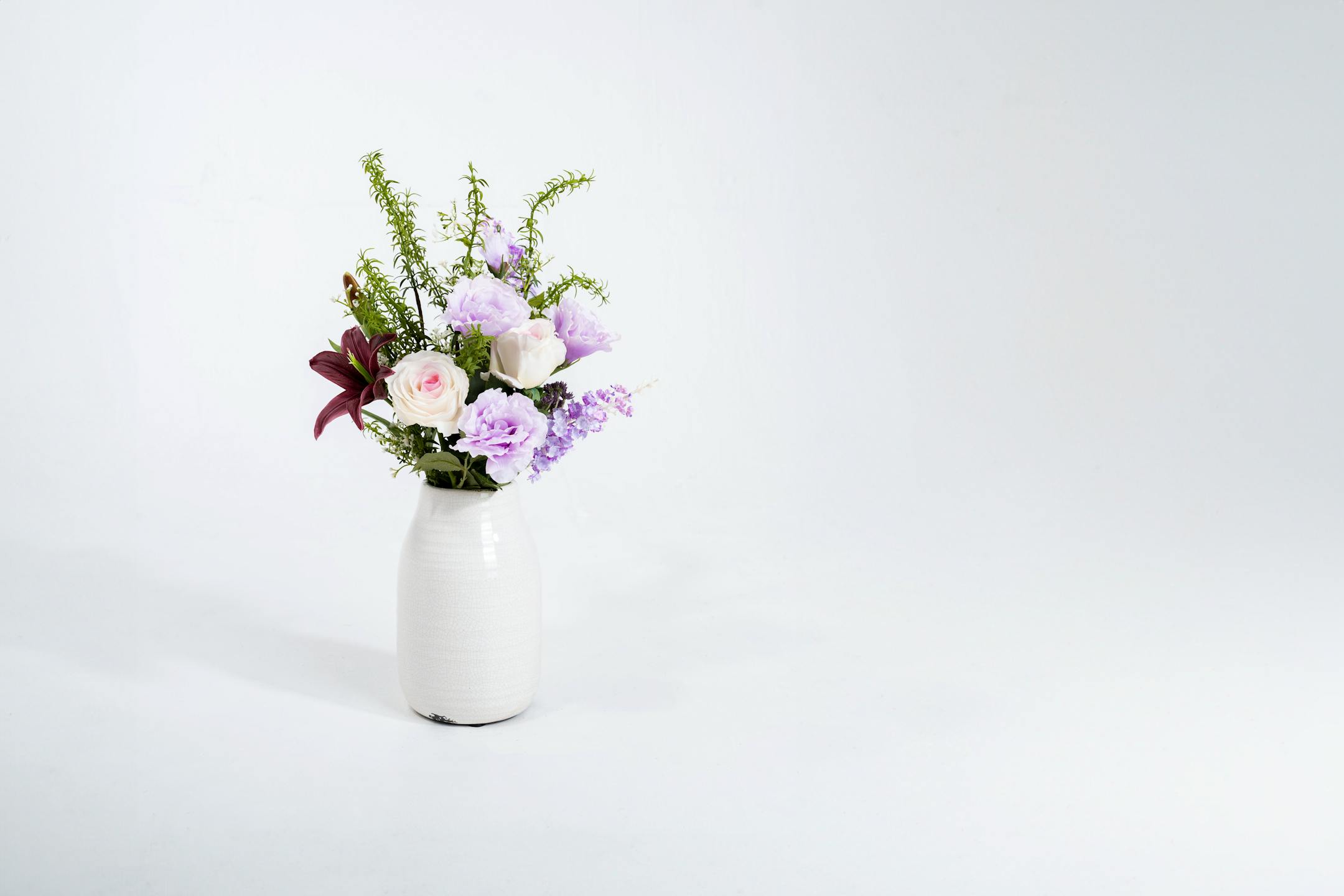 Artificial lilac bunch in white ceramic vase
