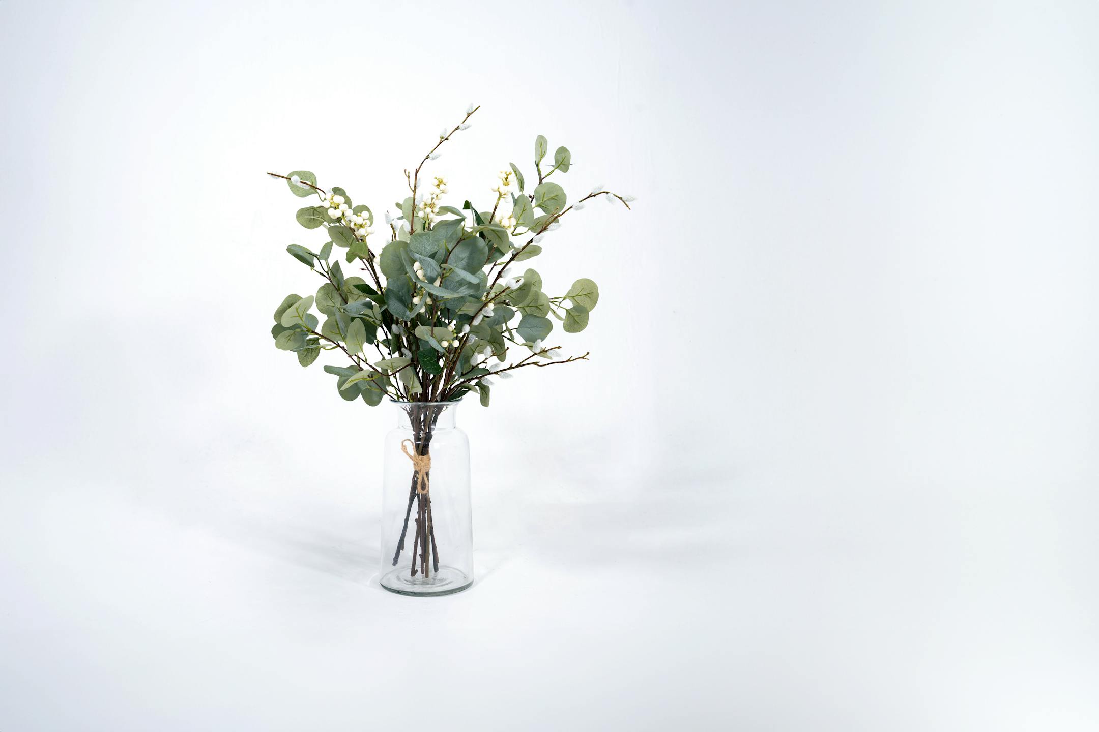 Faux winter foliage bunch in glass vase