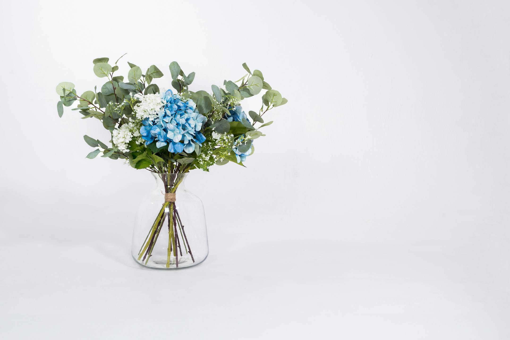 Artificial blue hydrangea bouquet in glass vase