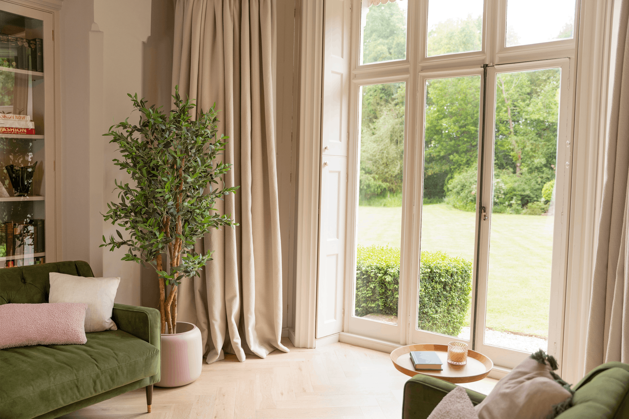 Faux olive tree in neutral living room with window