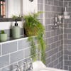 Artificial hanging plumosus fern in grey tiled bathroom