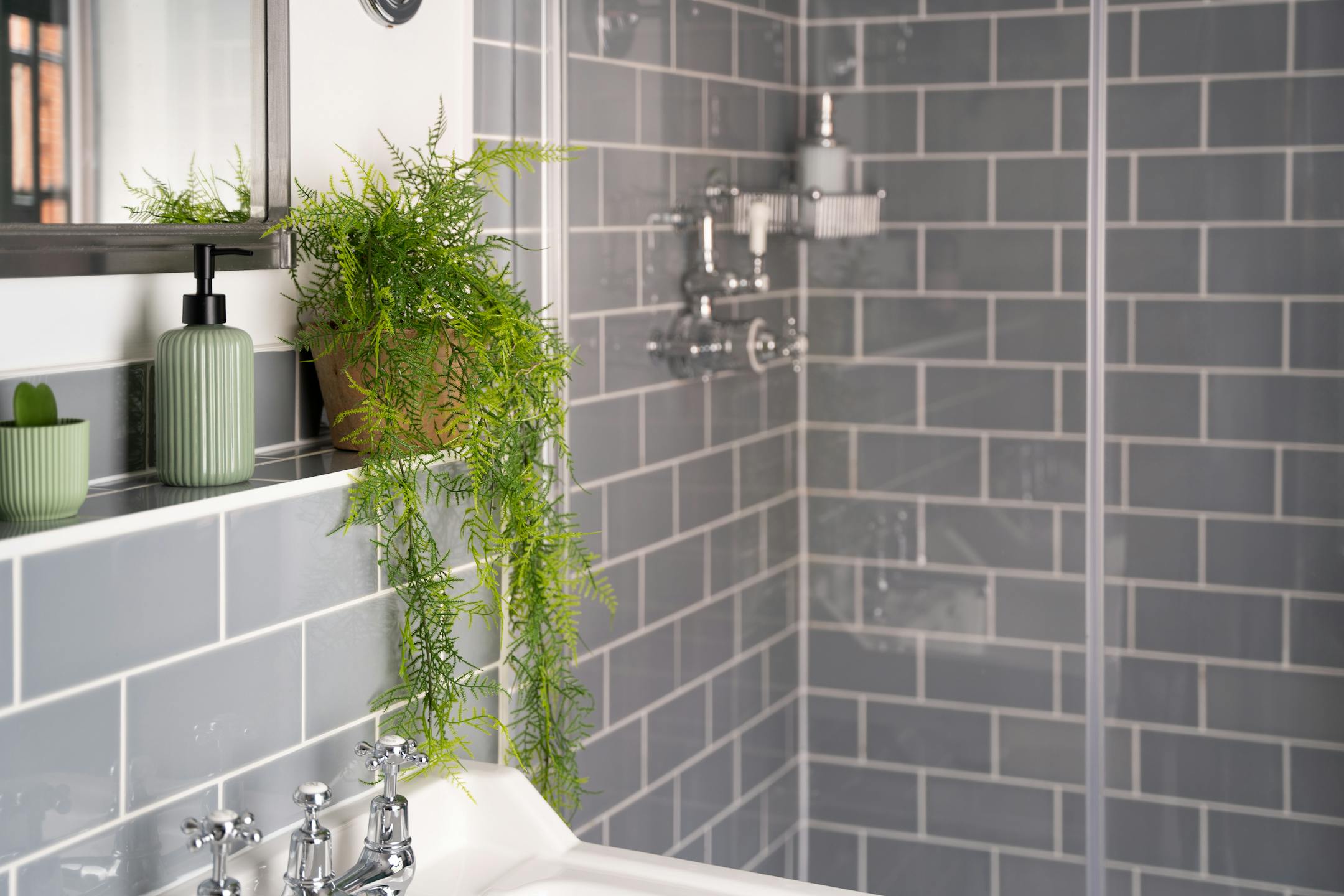 Artificial hanging plumosus fern in grey tiled bathroom