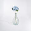 Blue artificial hydrangea stem in glass vase