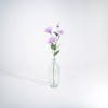 Purple artificial lisianthus stem in glass vase