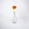 Single orange artificial sunflower stem in glass vase