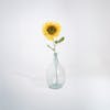Single yellow artificial sunflower stem in glass vase