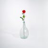 Red artificial rose stem in glass vase