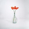 Three red artificial anthurium stems in glass vase