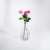 Three dark pink artificial rose stems in glass vase