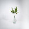 Three artificial laurel foliage sprays in glass vase