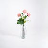 Three light pink artificial rose stems in glass vase