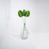 Three artificial pothos leaves in glass vase