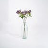 Three purple artificial cow parsley stems in glass vase