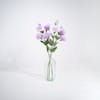 Three purple artificial lisianthus stems in glass vase