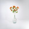 Three triple orange artificial sunflower stems in glass vase