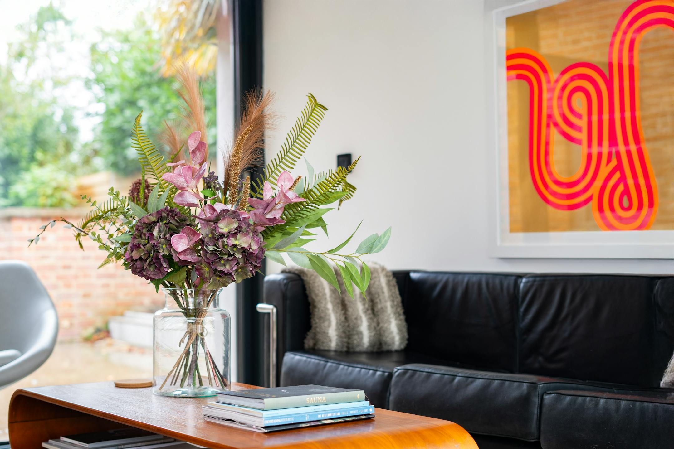 Artificial woodland walk bouquet in white living room with black leather sofa
