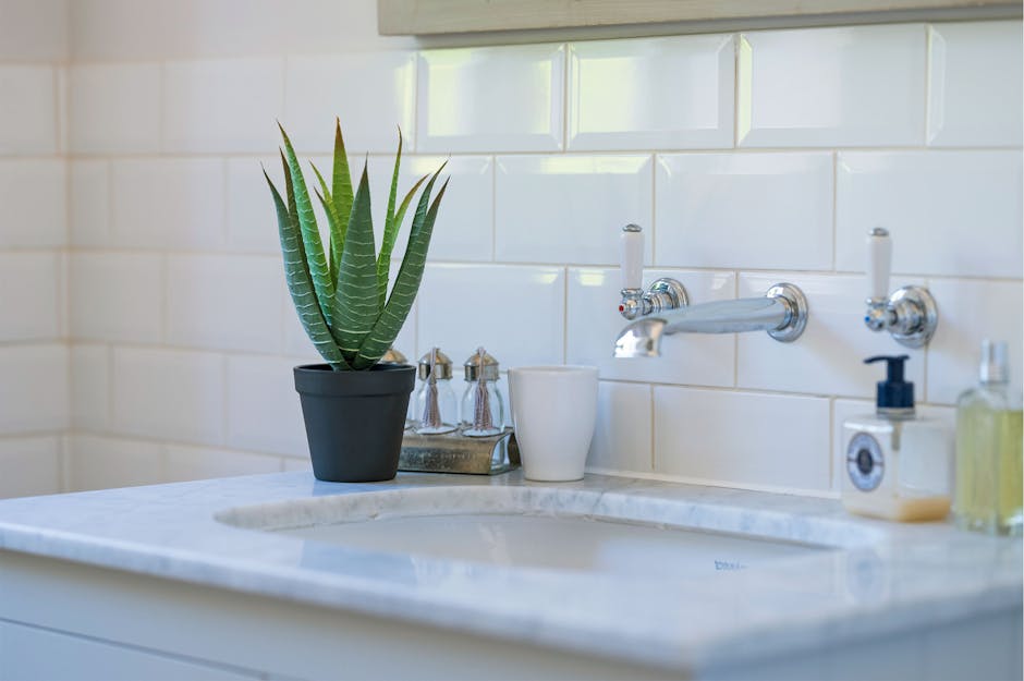 Artificial aloe vera plant on a bathroom sink countertop with white tiles