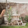 Large artificial areca palm outside by wood-fired hot tub