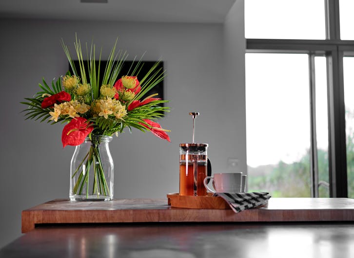 Artificial bahama mama bouquet on wooden kitchen island with cafetiere