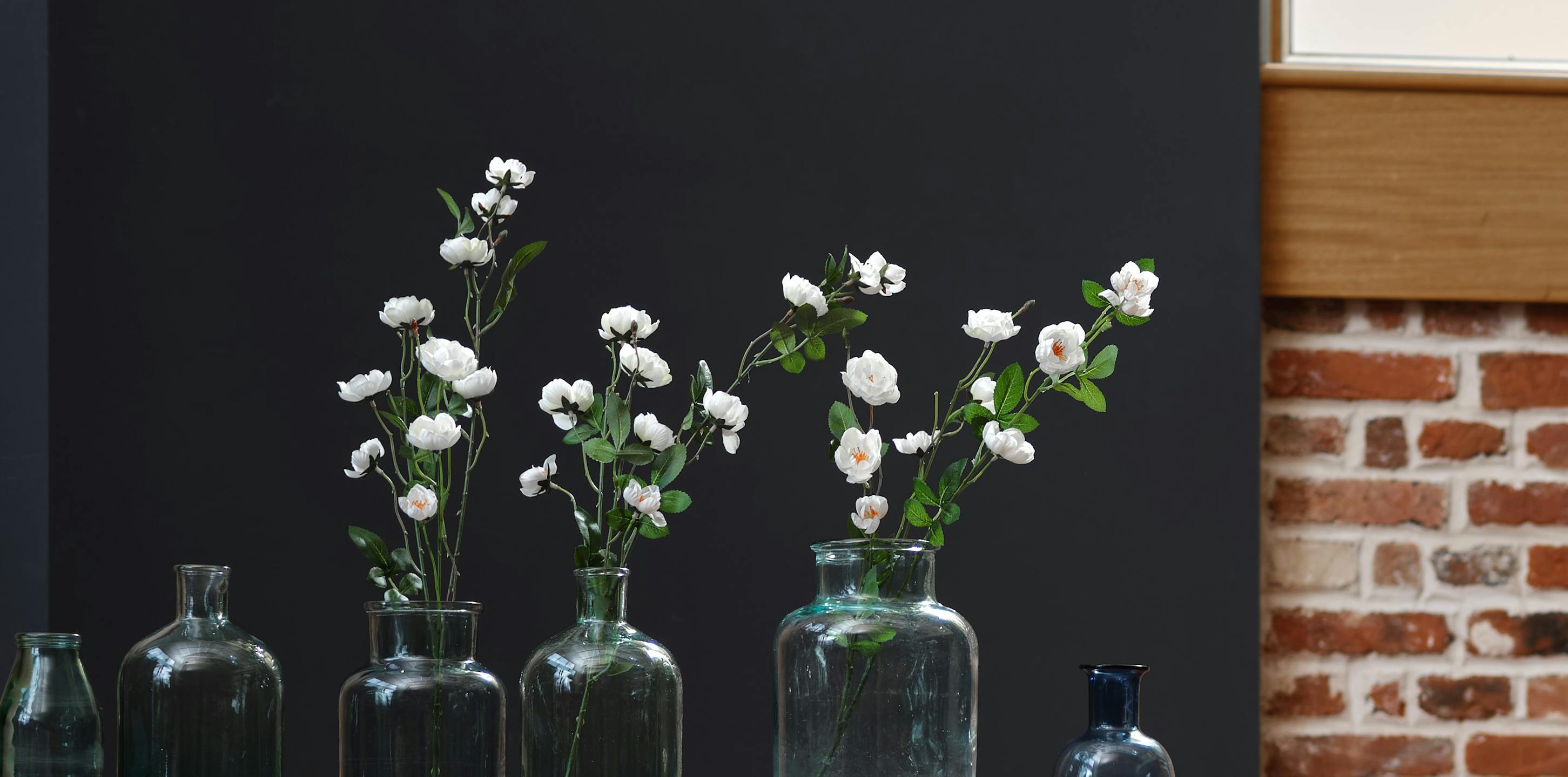 Artificial white blossom stems in glass bottles