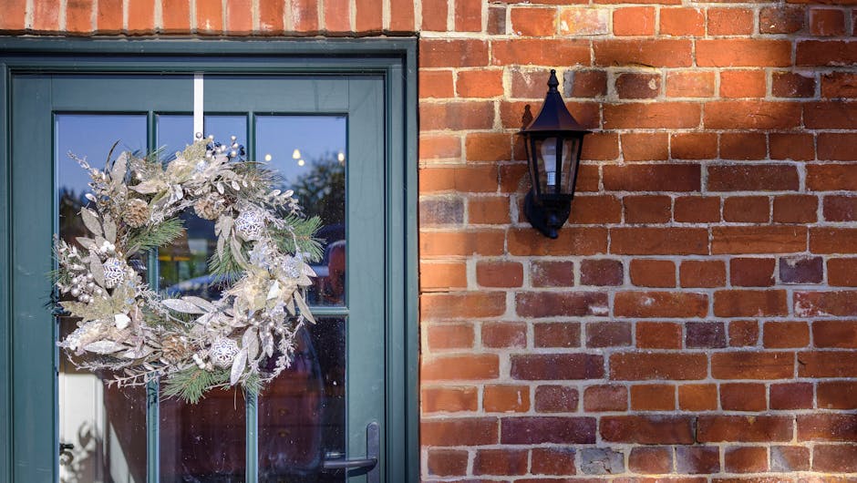 Glittery Christmas wreath hanging on green door on red brick house