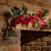 Blooming Artificial fiesta-red poinsettia and pinecone garland over fireplace