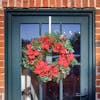 Christmas fiesta poinsettia and pine cone faux wreath hanging on green glass frontdoor