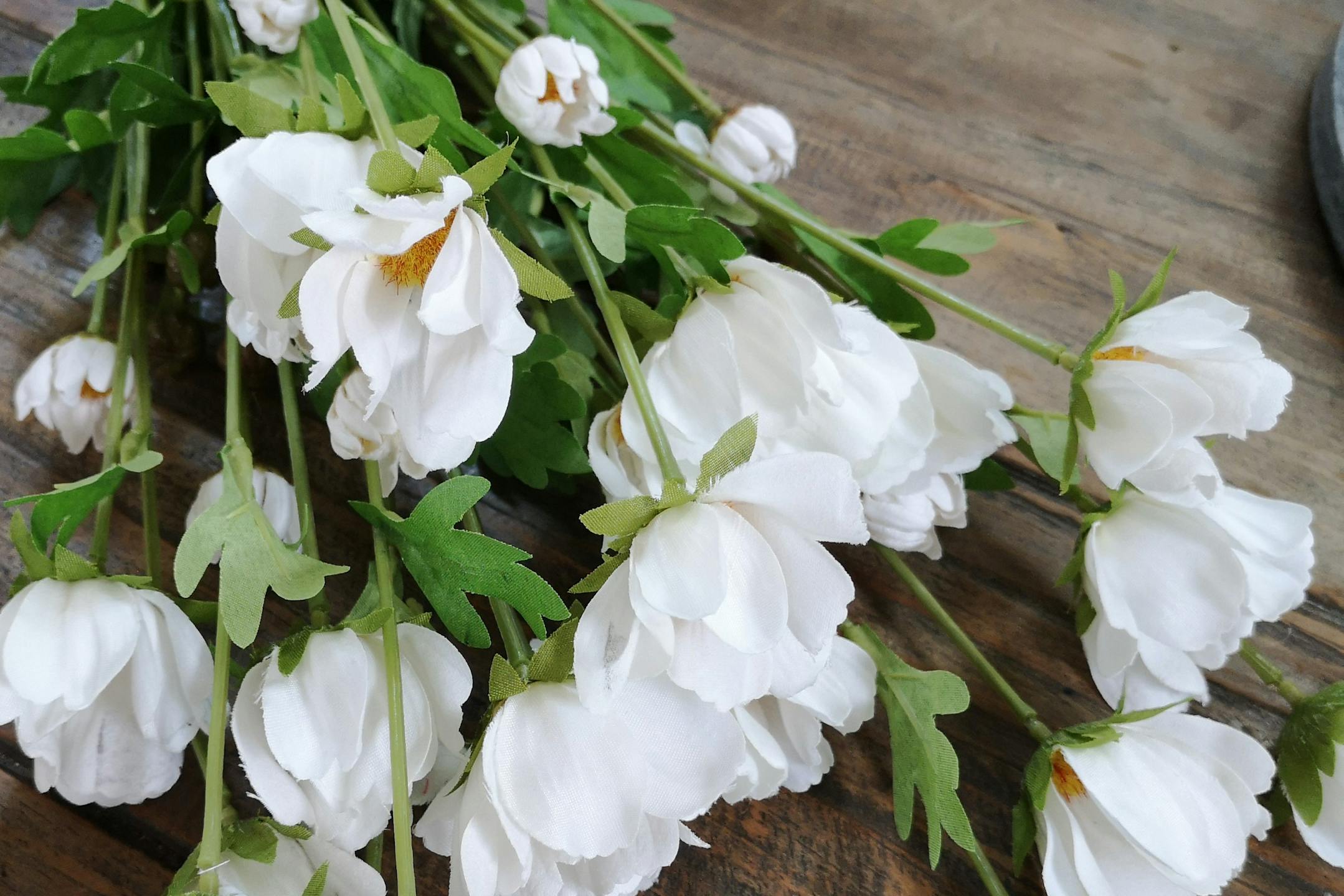 Artificial white cosmo flowers on wooden table