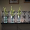 three faux foliage sprays in glass vases on kitchen worktop