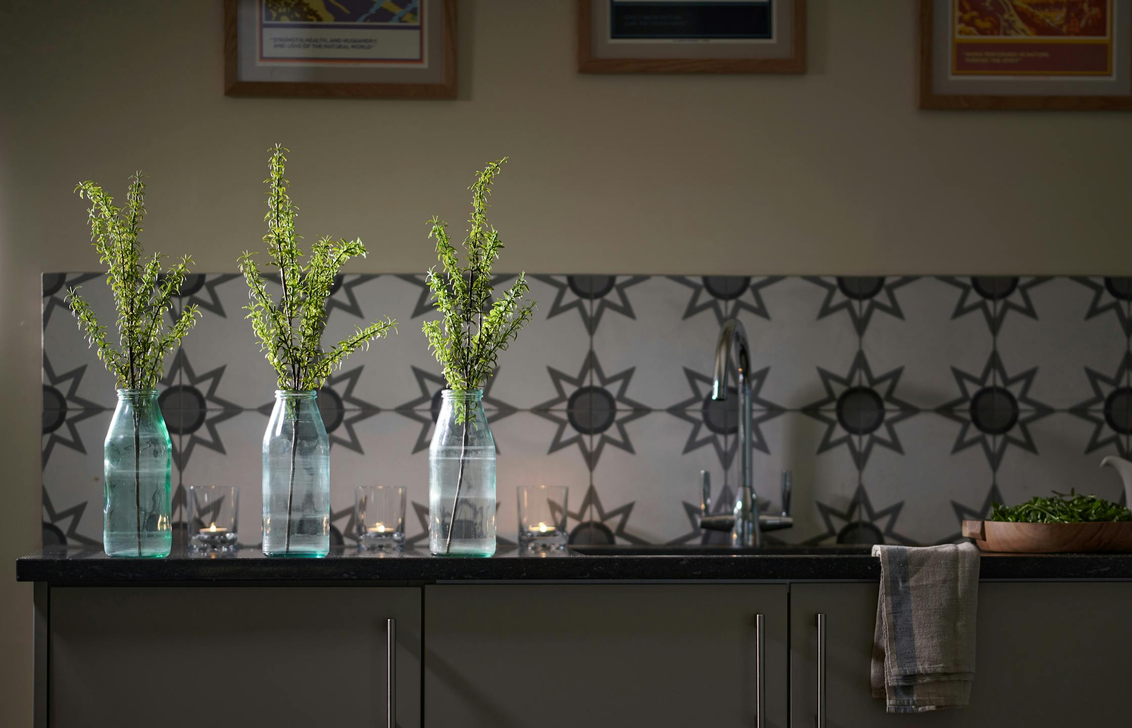 three faux foliage sprays in glass vases on kitchen worktop