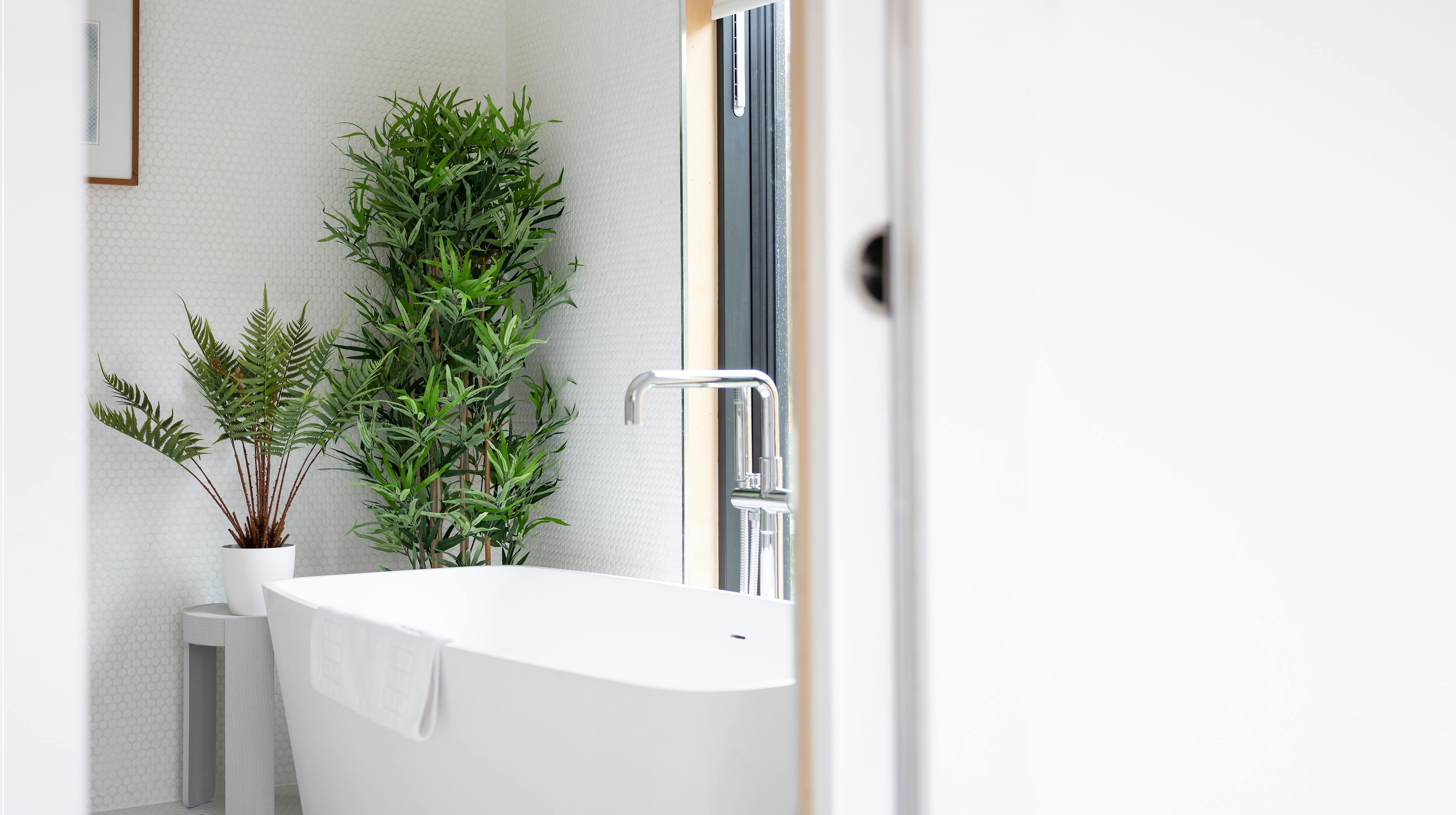 Faux oriental style bamboo plant in modern bathroom with fern plant